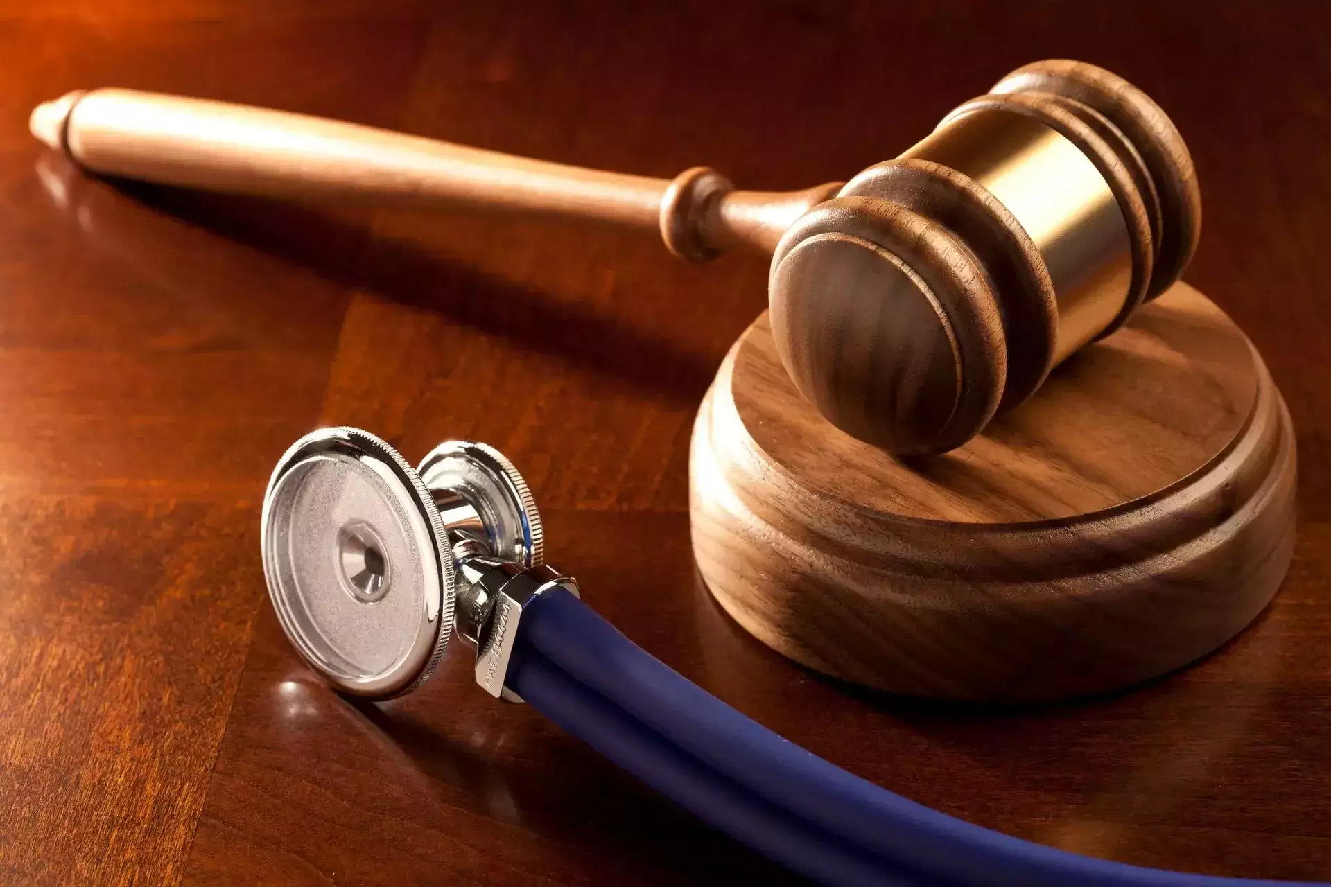 Wooden judge's gavel and a medical stethoscope on a wooden desk.