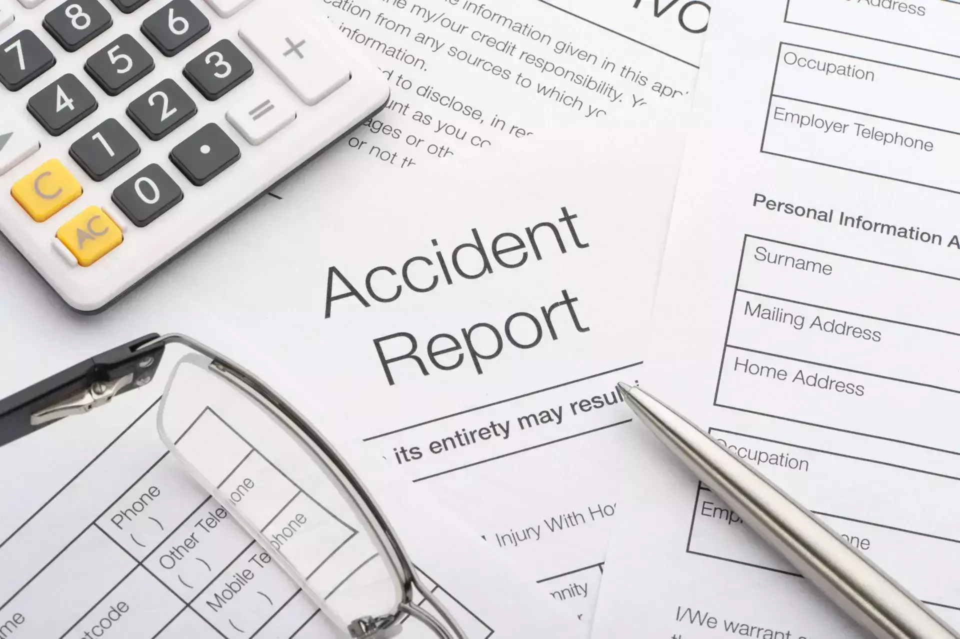 Accident report form with calculator, pen, and eyeglasses