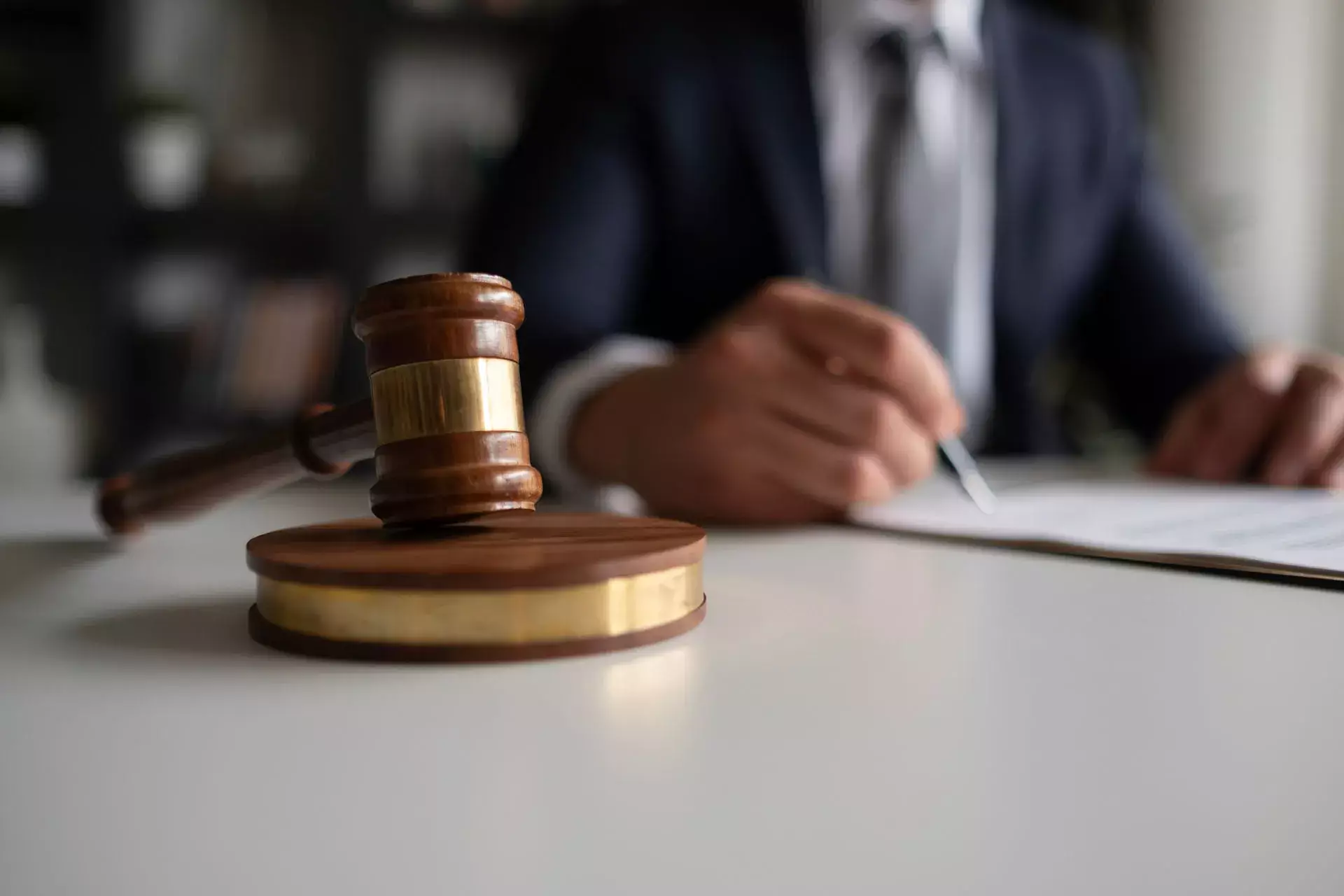 Judge’s gavel on a desk with a legal professional reviewing documents in the background