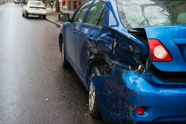 A heavily damaged rear side of a blue car.