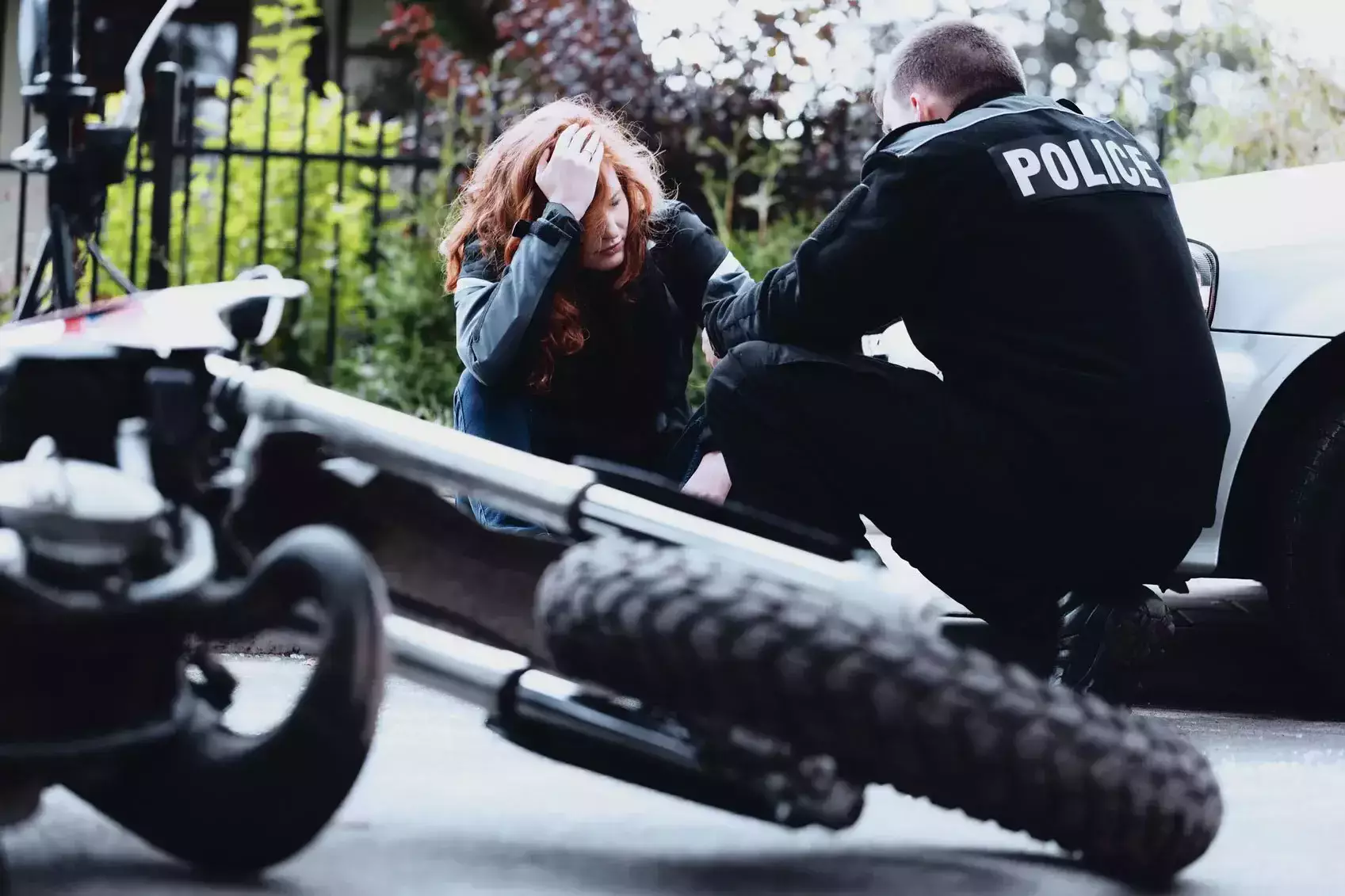 Un policía consolando a una mujer junto a una motocicleta accidentada.