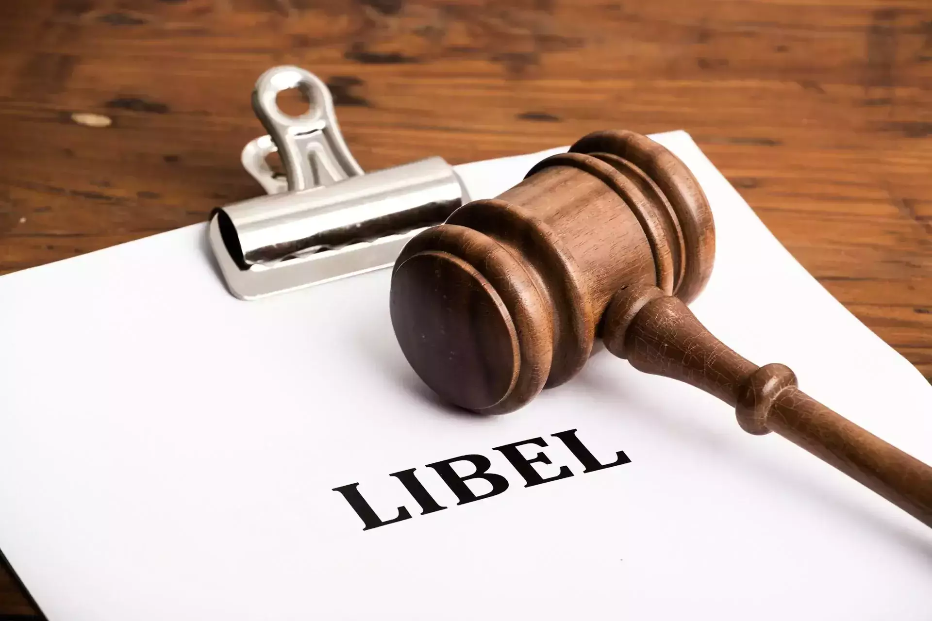 A paper with 'Libel' and a wooden gavel on a desk.