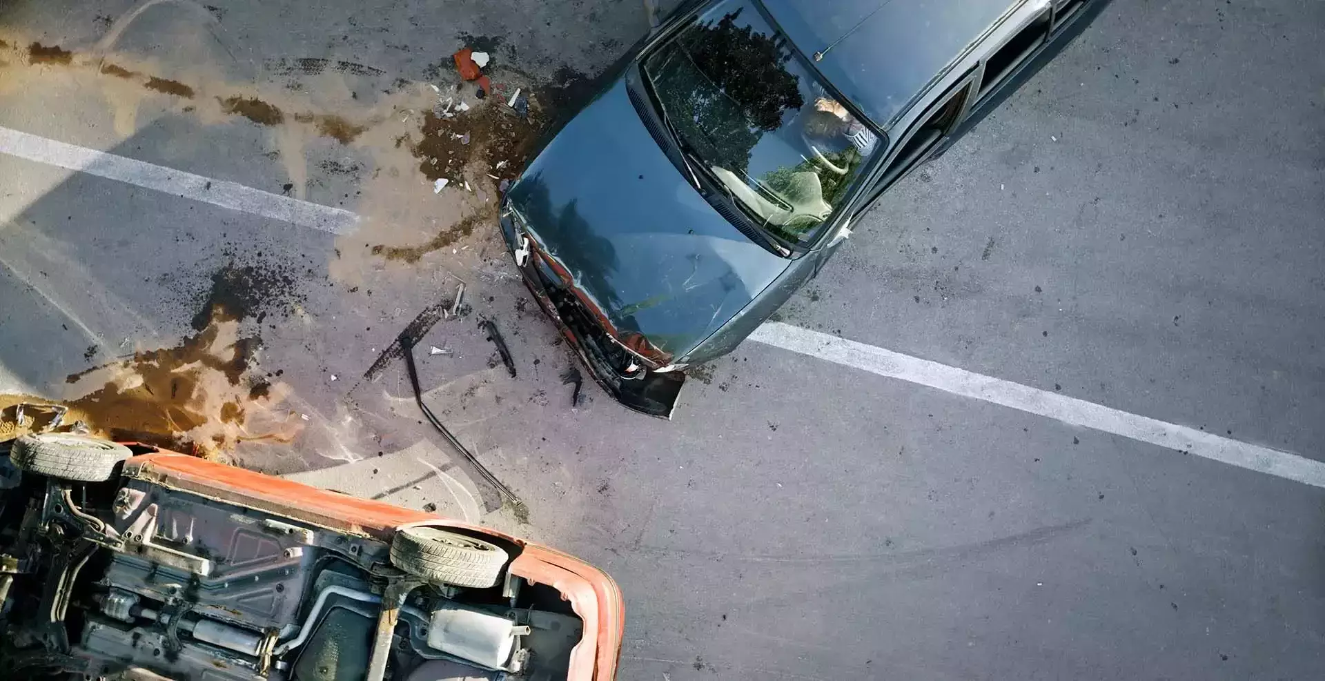 Aerial view of a car crash involving an overturned red vehicle.