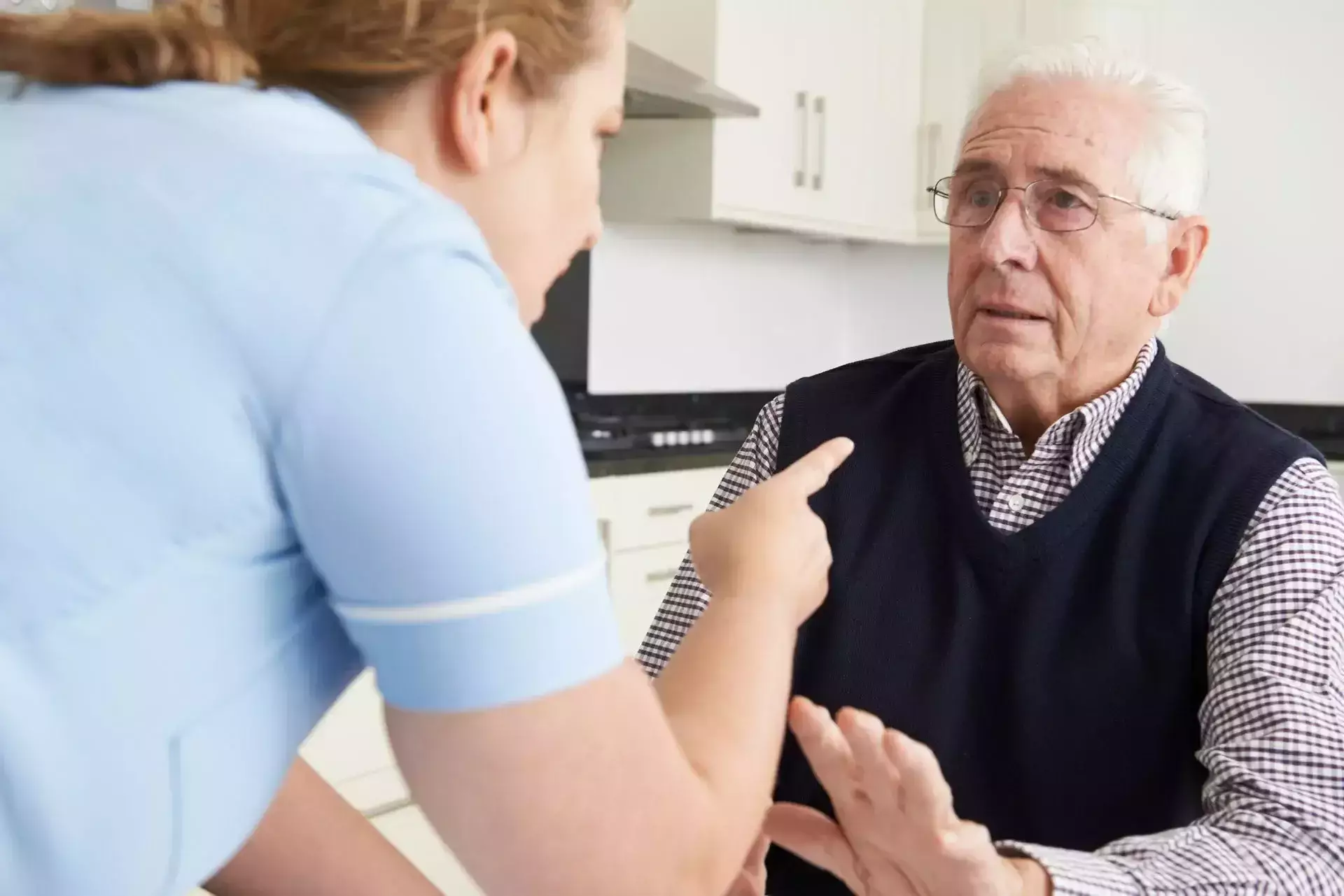 A caregiver pointing her finger at an elderly man who looks upset.