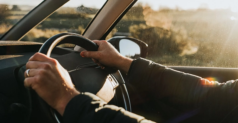 Driver holding the steering wheel while driving a vehicle.